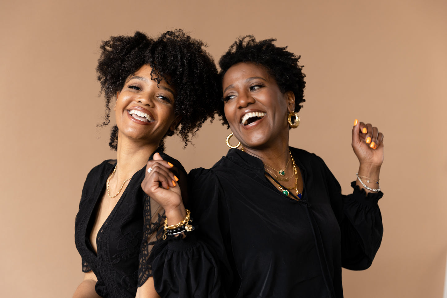 Two Black Women, tight curly, coily hair smiling 